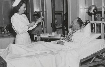 Nurse prepares syringe to give dose to patient in hospital bed