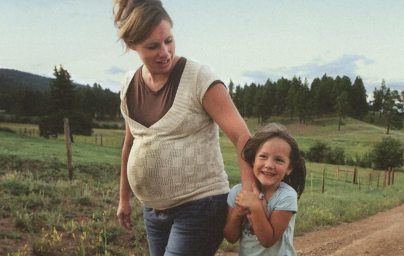 Pregnant mother holding hands with young girl