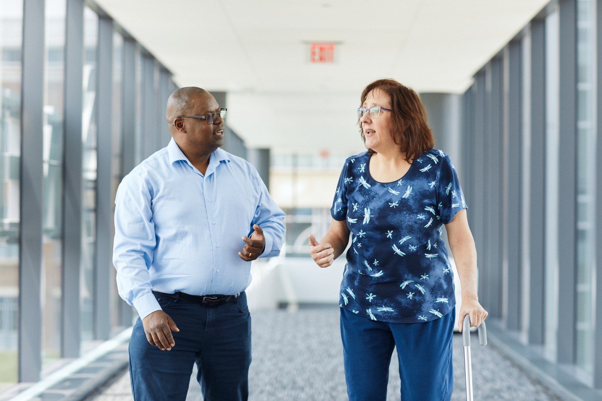man and woman walking in the office. The woman has a cane.