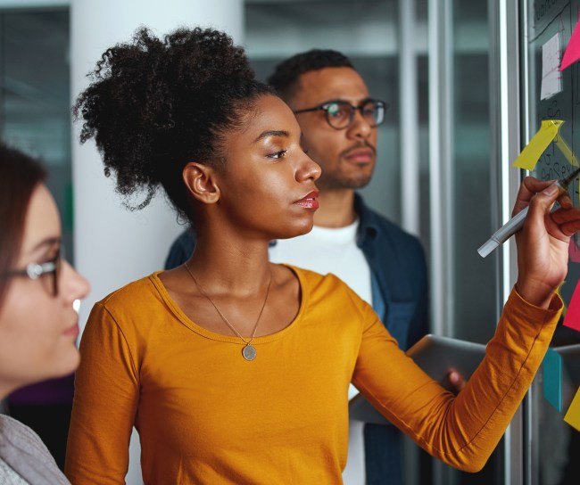 Diverse people looking at board with sticky notes
