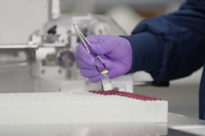 person picking up vial with tweezers