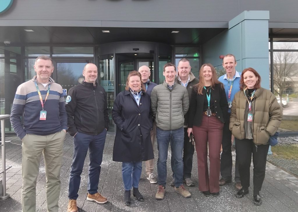 group of 9 people standing in front of office and smiling