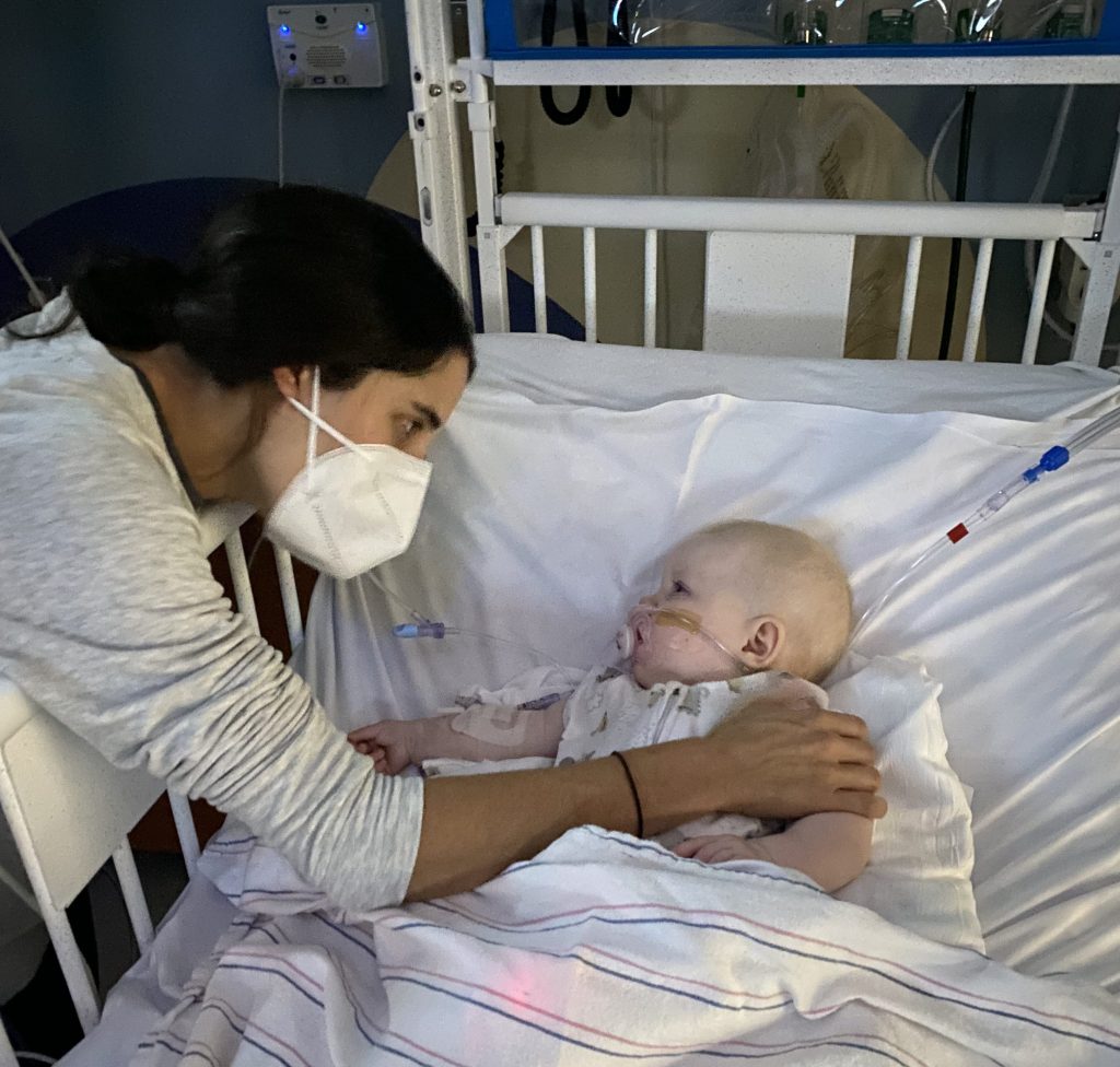 women wearing a mask comforting a child in hospital bed
