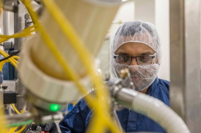 Man wearing hair net and mask working in a manufacturing facility