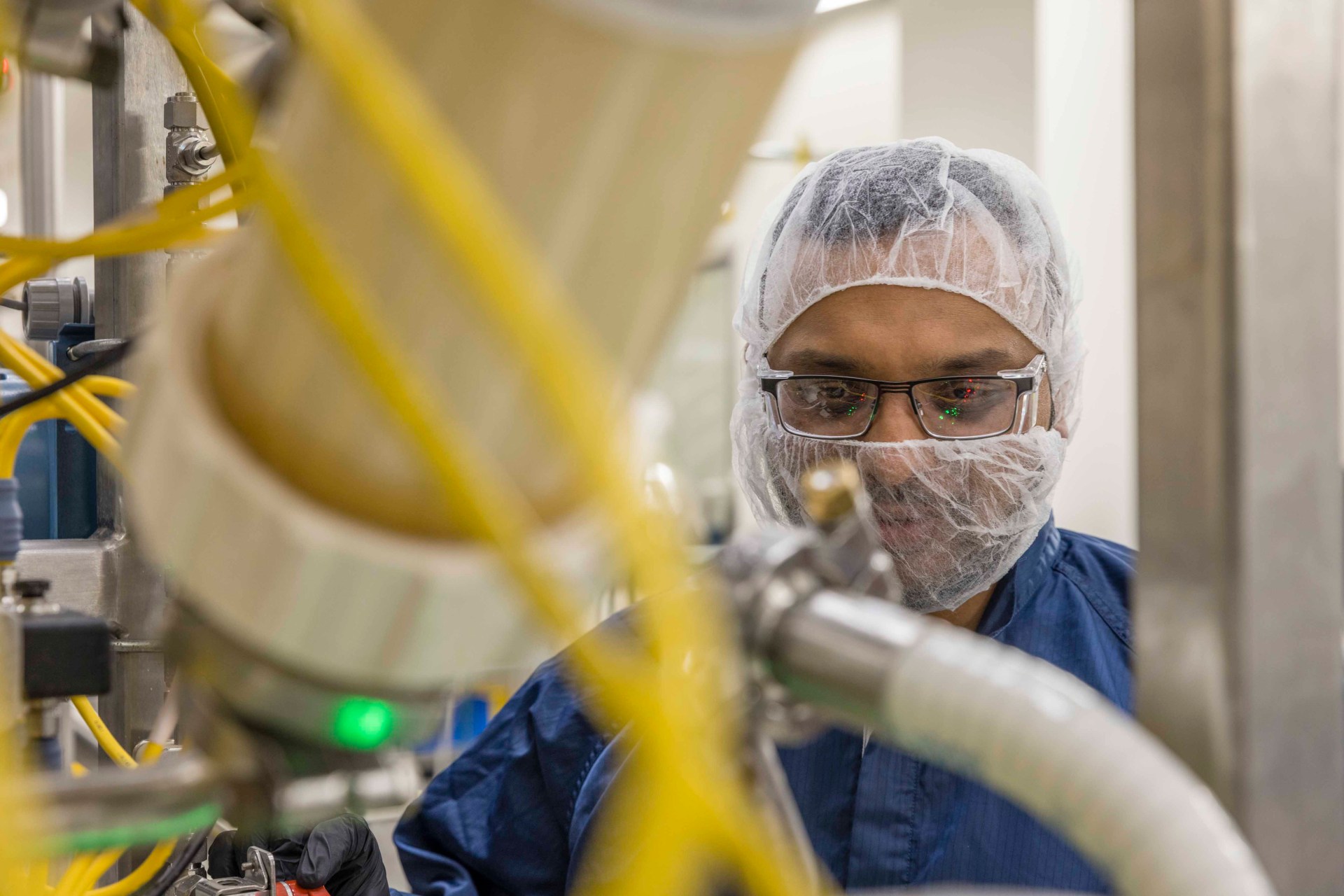 Man wearing hair net and mask working in a manufacturing facility