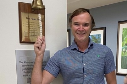 Chet Kitchen standing indoor smiling at the camera ready to ring the bell.