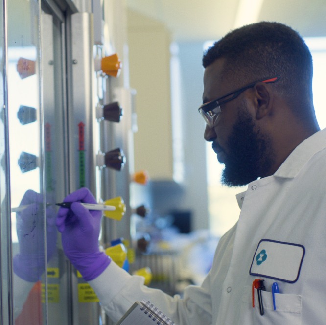person wearing glasses and white coat writing on the board