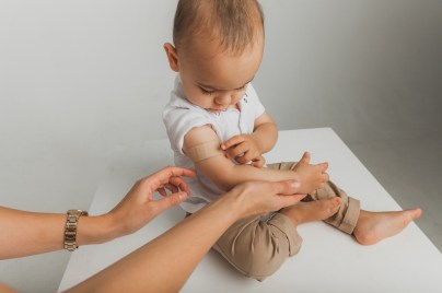baby sitting down on table with band aid on right arm