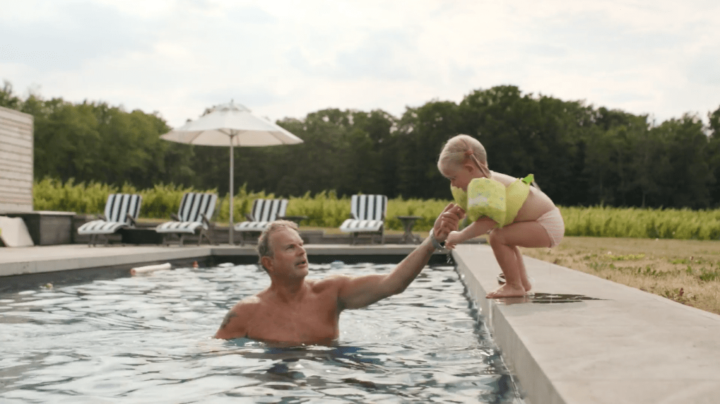 John Bald in a swimming pool and holding hands with small grandchild 