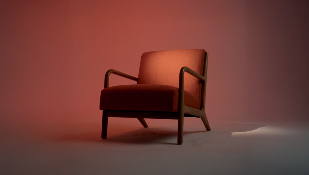 a single red chair with arm rests and a spotlight on it