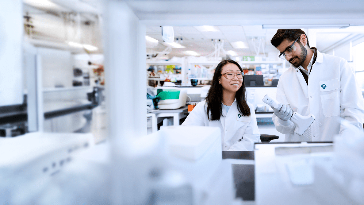 two scientists wearing lab coats working in a lab